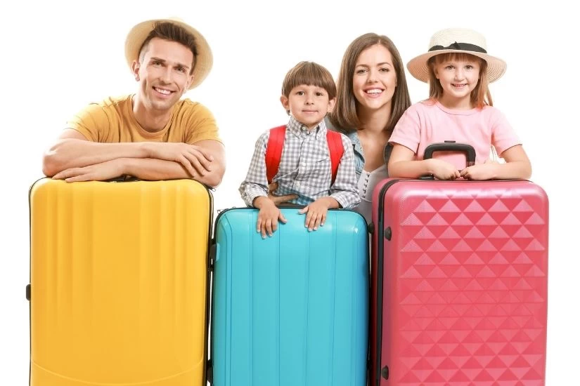 Porodica spremna za letovanje naslonjena na kofere.